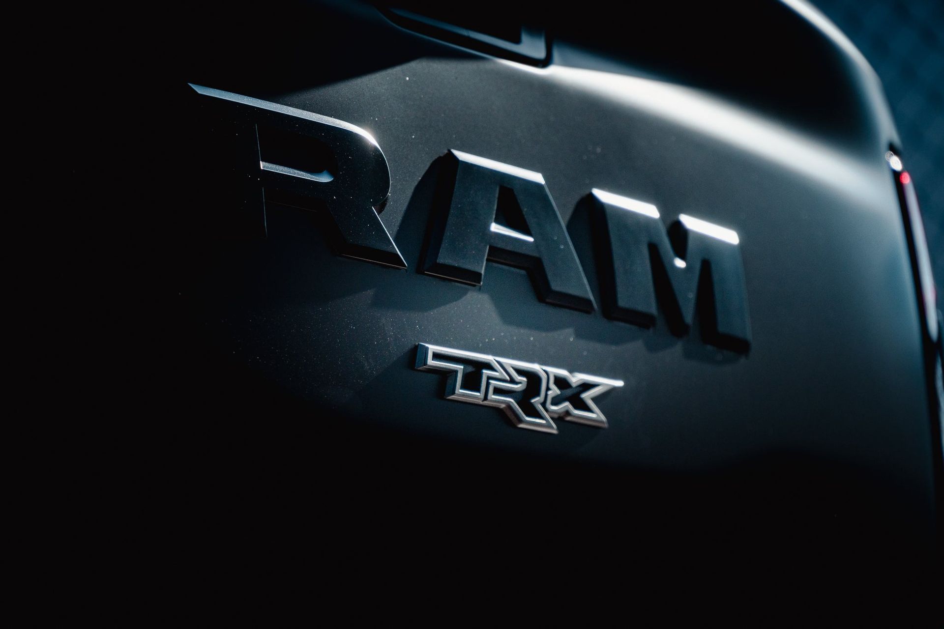 Close-up of a black RAM TRX truck badge with metallic lettering and blue highlights