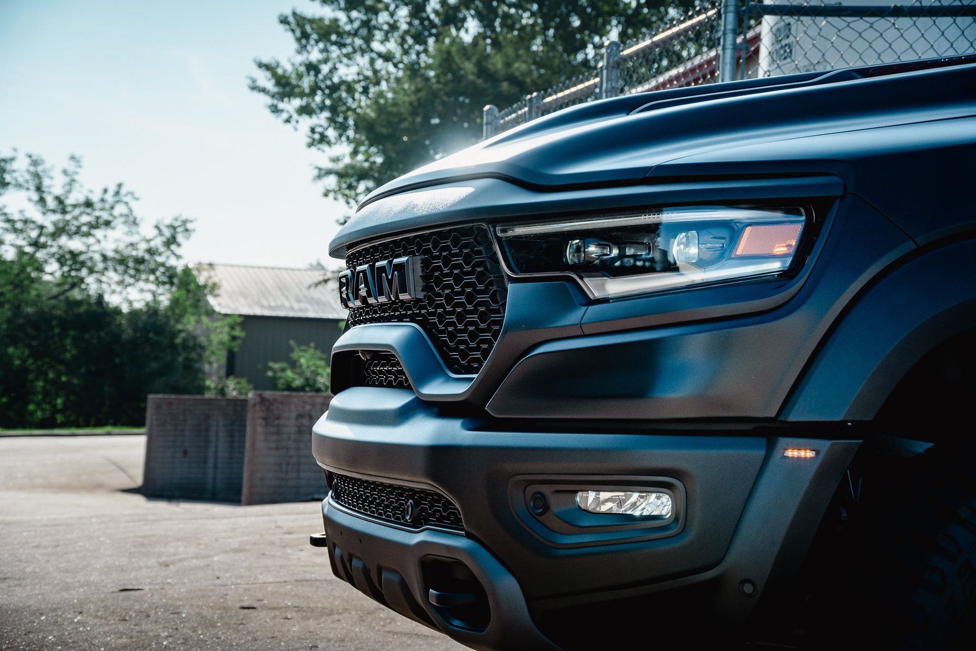 Close-up of a black pickup truck’s front grille and headlight parked outdoors.