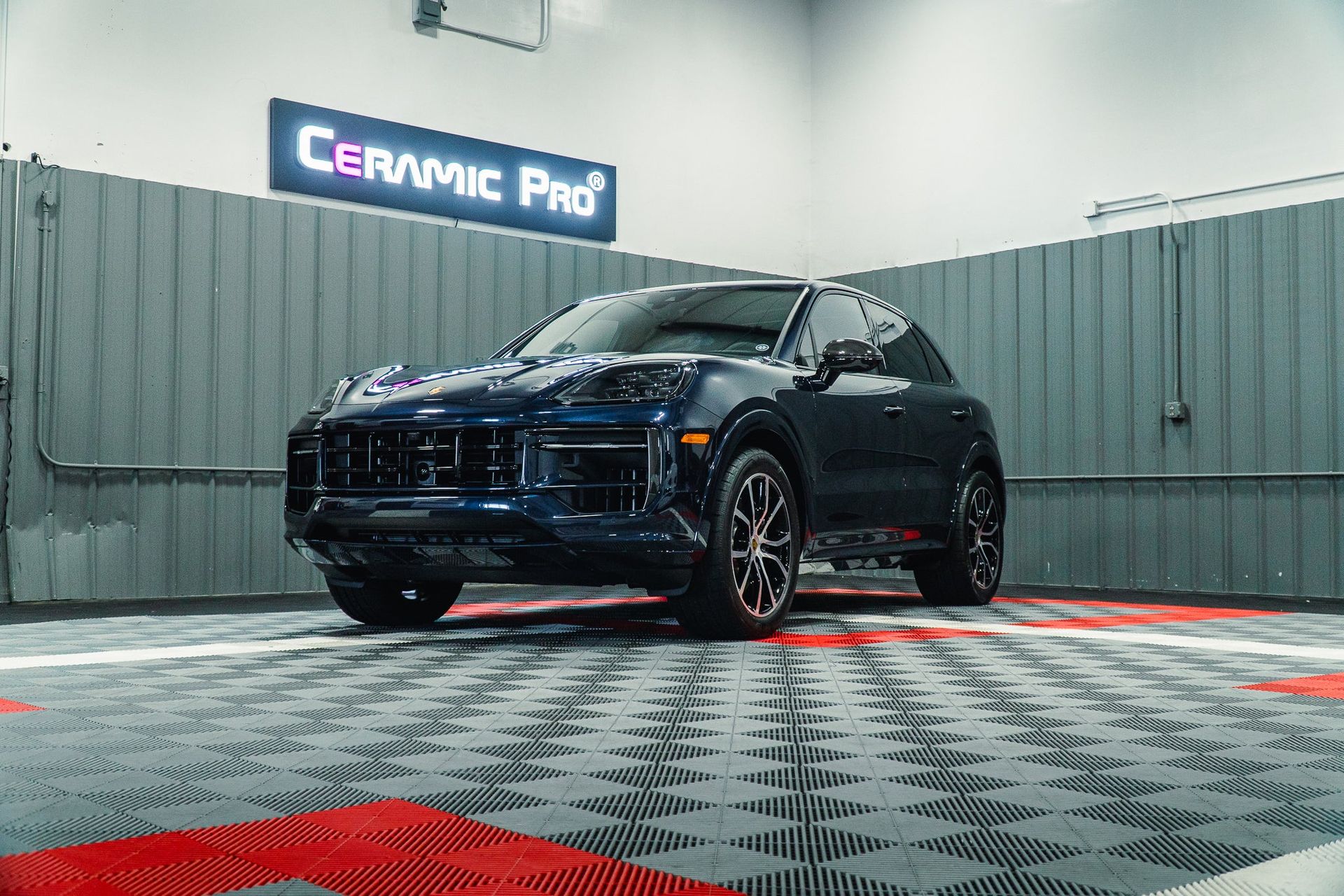 Black SUV in a detailing studio with gray curtains and a red-and-silver checkered floor