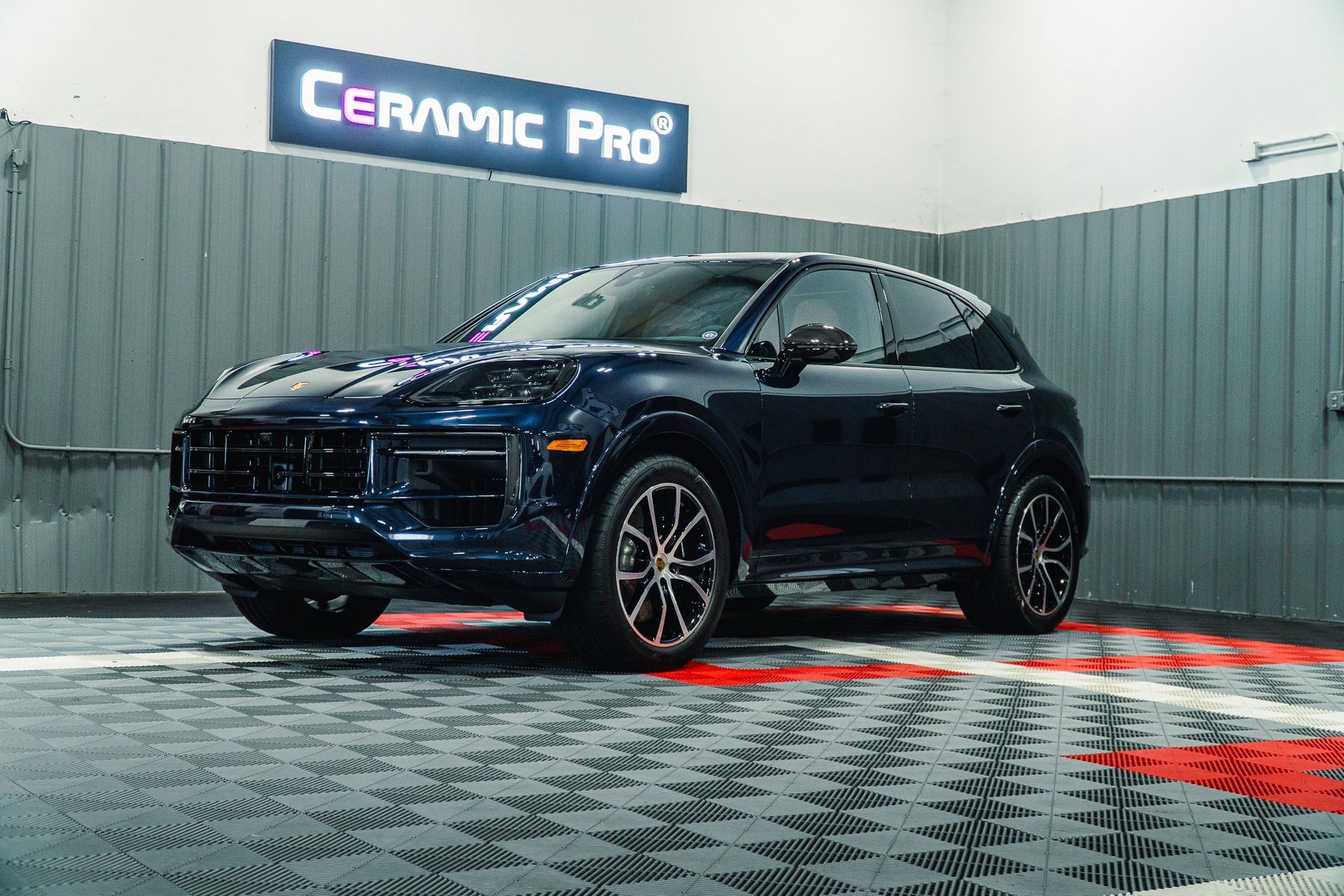 Black SUV on a checkered floor in front of a Ceramic Pro sign.