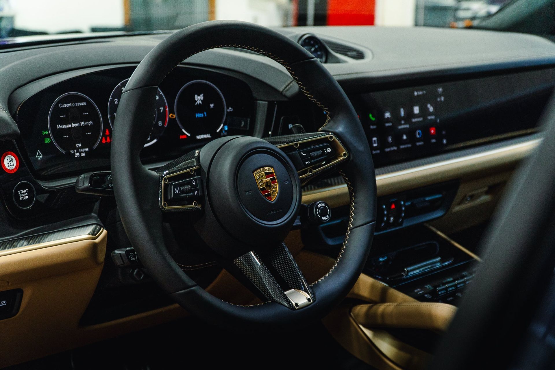 Porsche sports car interior with steering wheel, dashboard display, and tan leather seats