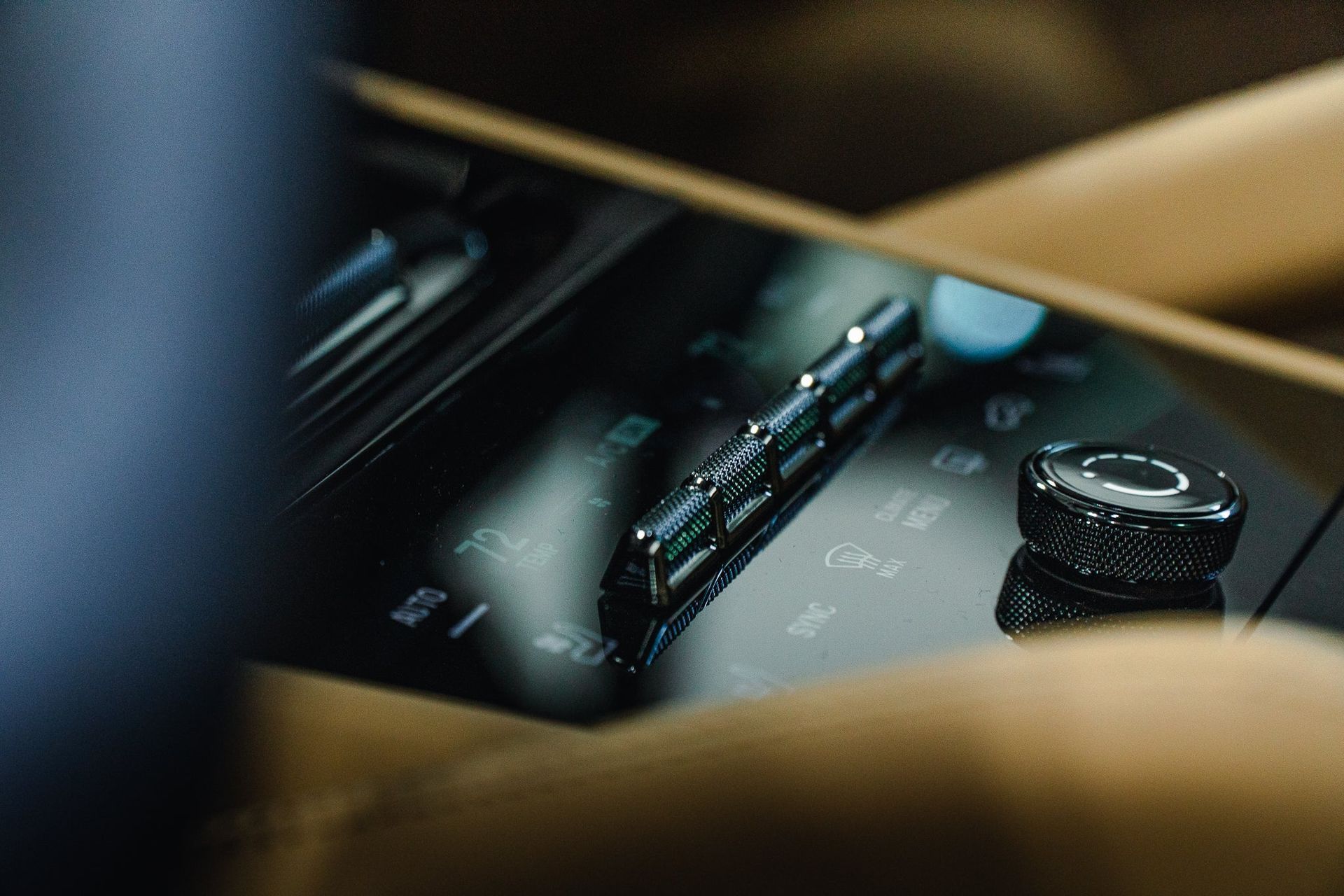 Close-up of a hand adjusting a car dashboard control knob with illuminated buttons