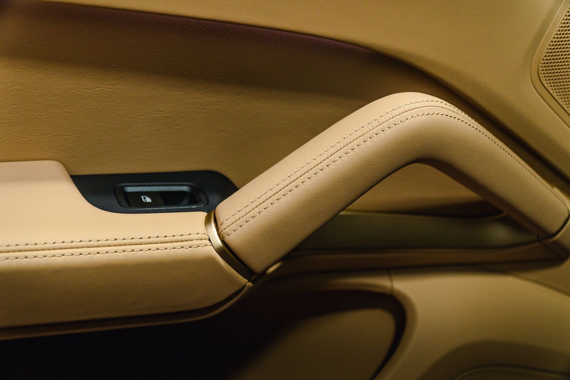 Close-up of a beige car door armrest and handle with black trim