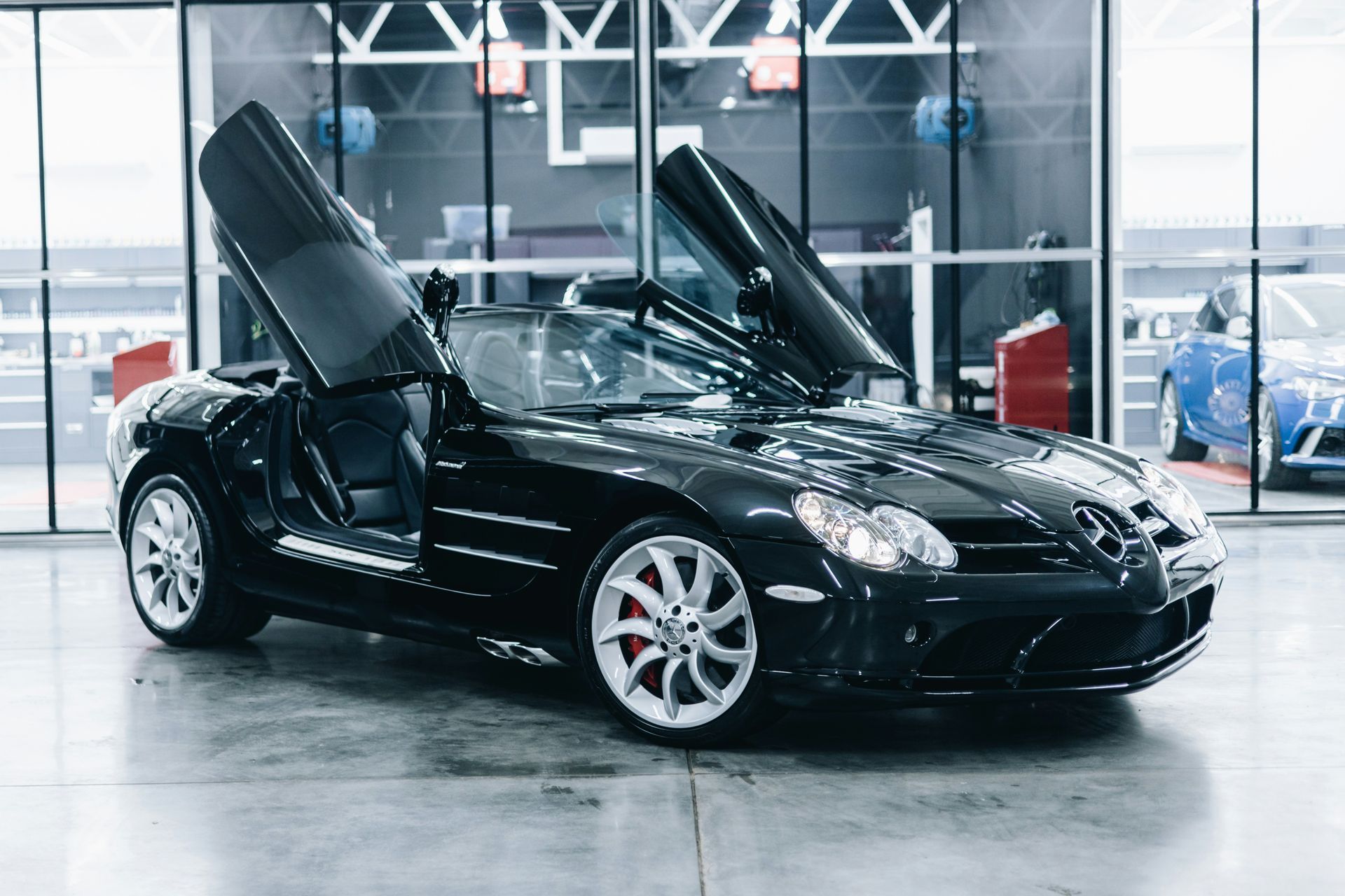 Black sports car with gullwing doors raised in a bright showroom