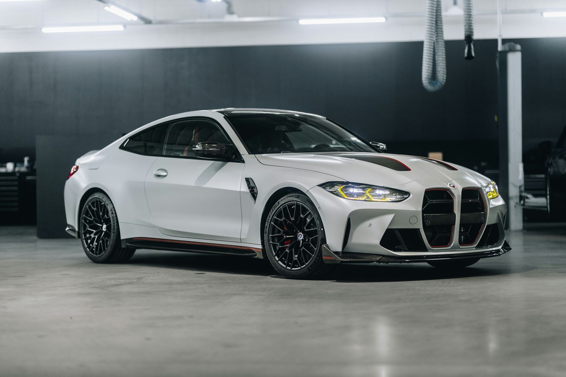 White BMW sedan with black wheels parked in a dim garage