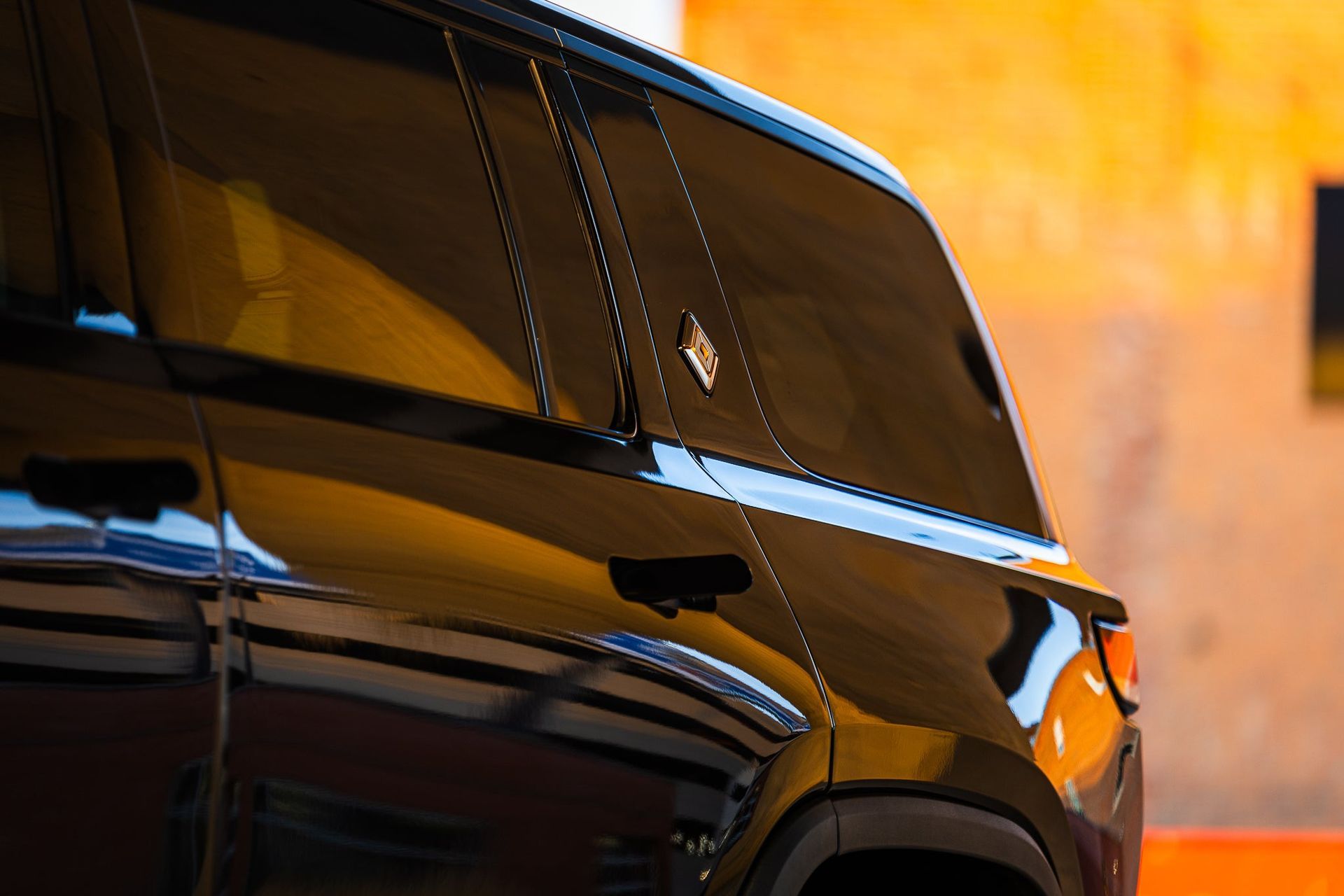 Black SUV rear side in close-up against a warm orange background