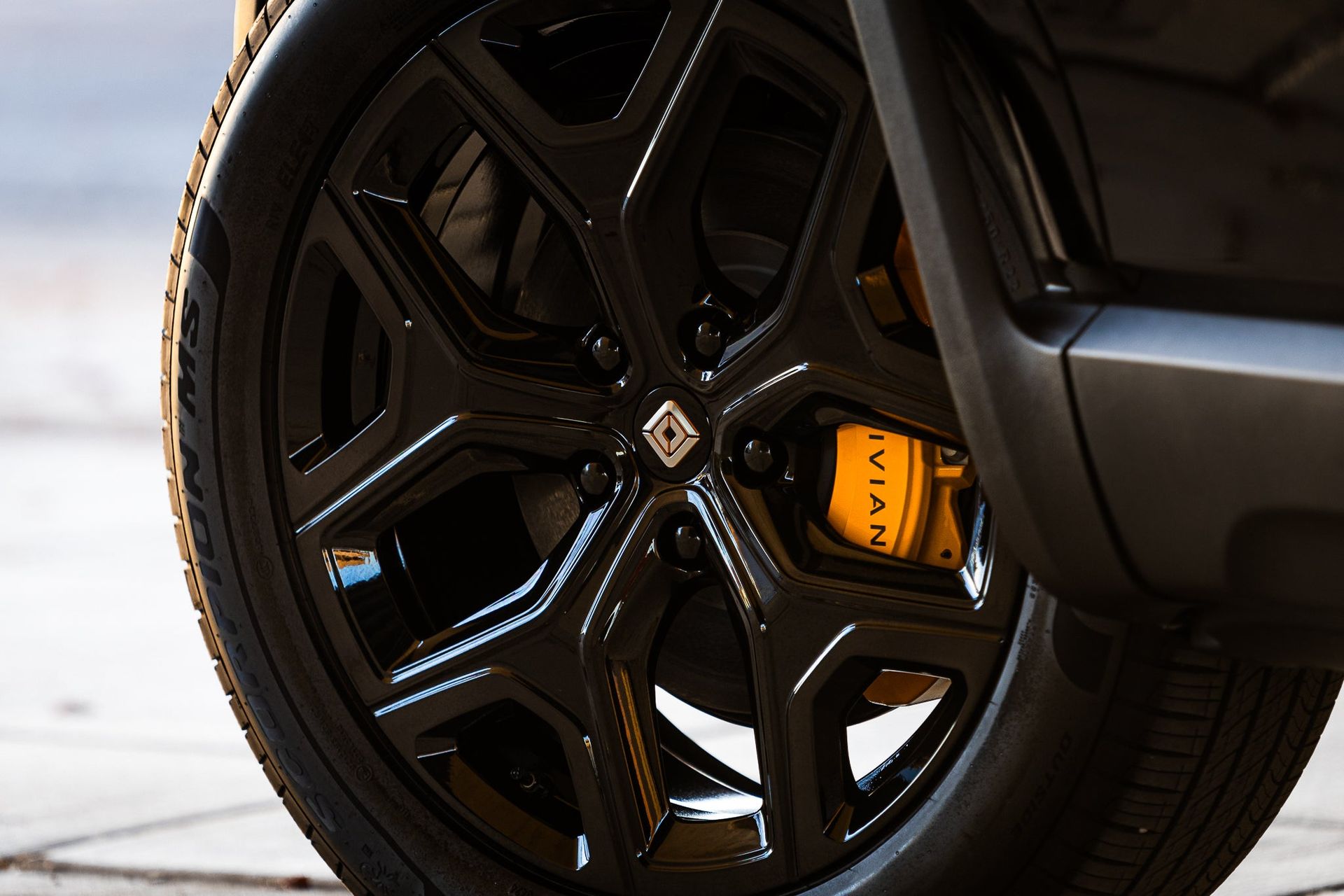 Close-up of a black car wheel with orange brake caliper and glossy rim