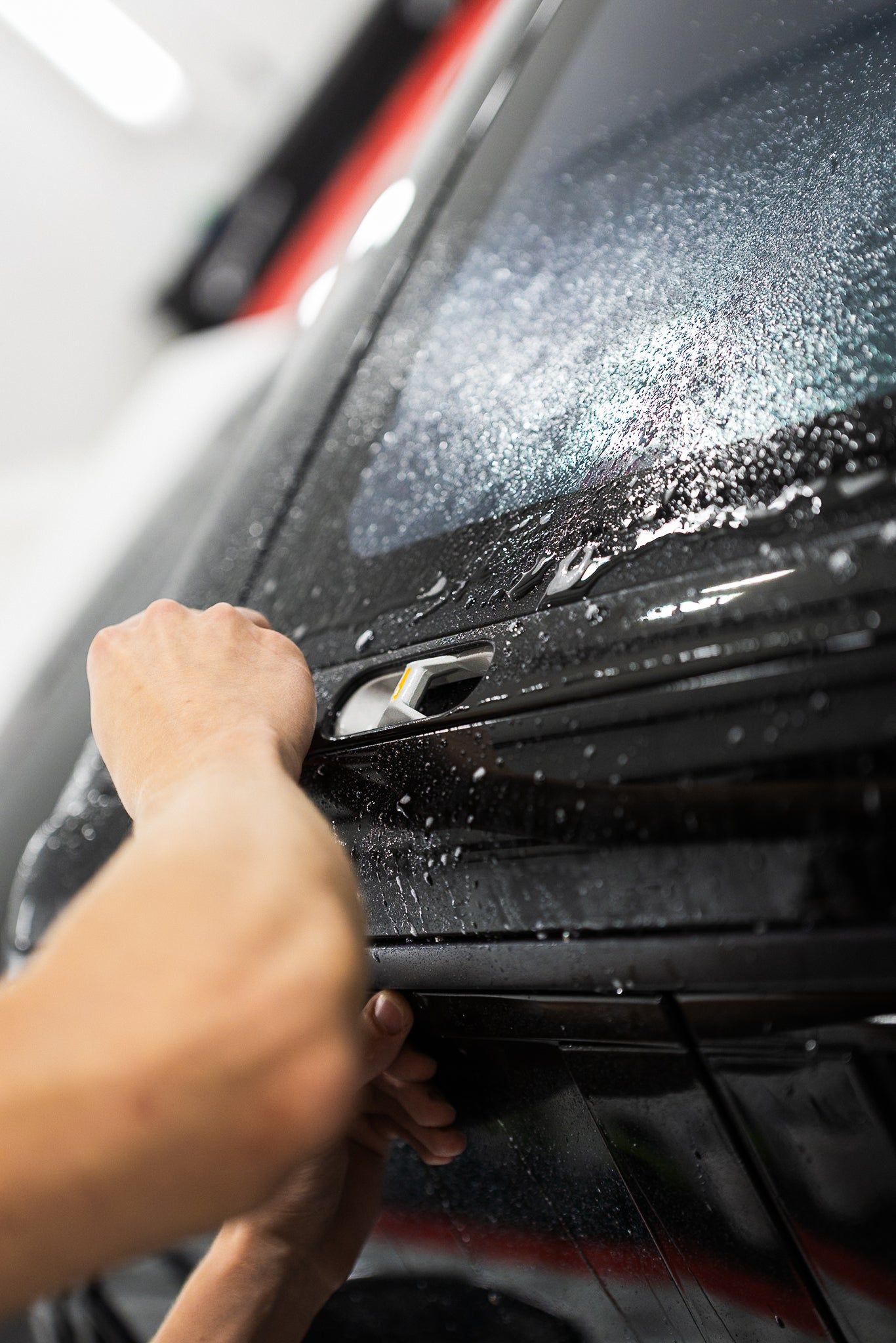 Hand washing a black car door with soap and water