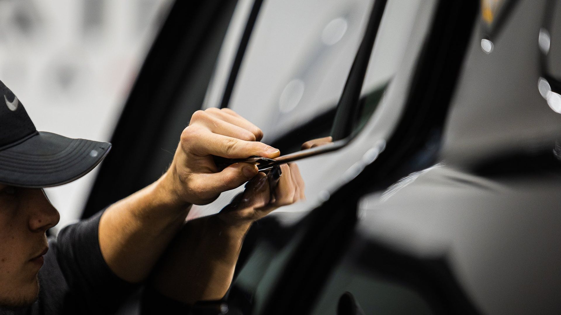 Person polishing a black car door with a cloth, close-up of the hand and glossy surface.