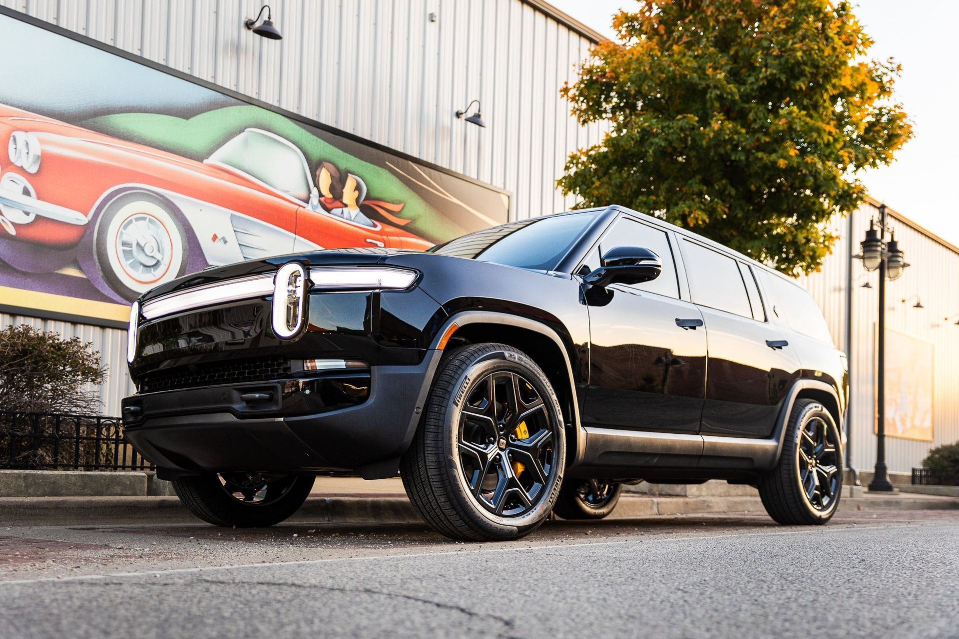 Black SUV parked outside a building with a vintage car mural in the background