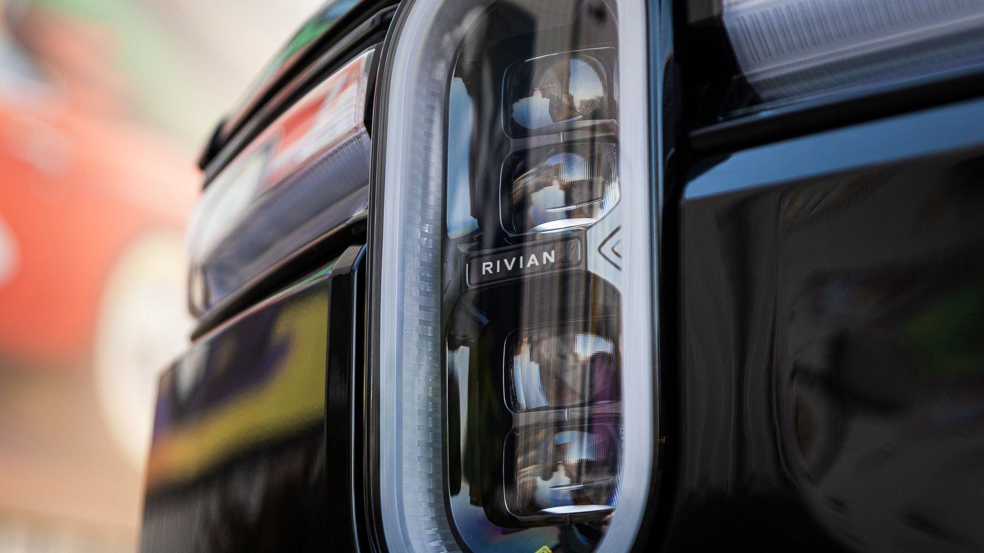 Close-up of a black Rivian vehicle’s rear taillight and body panel.