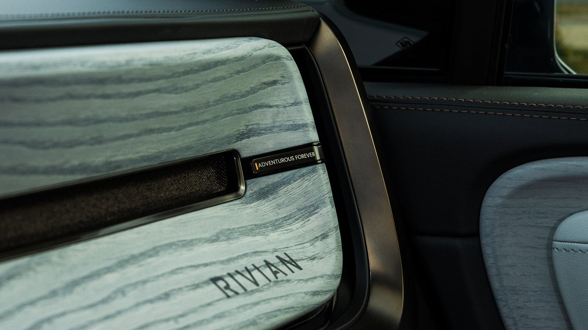 Close-up of a Rivian vehicle interior with striped light gray seat upholstery and black trim.
