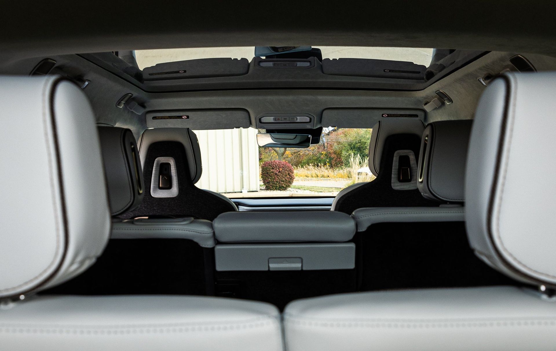 View from a car’s rear cargo area toward the front seats and sunroof, with light gray interior upholstery.