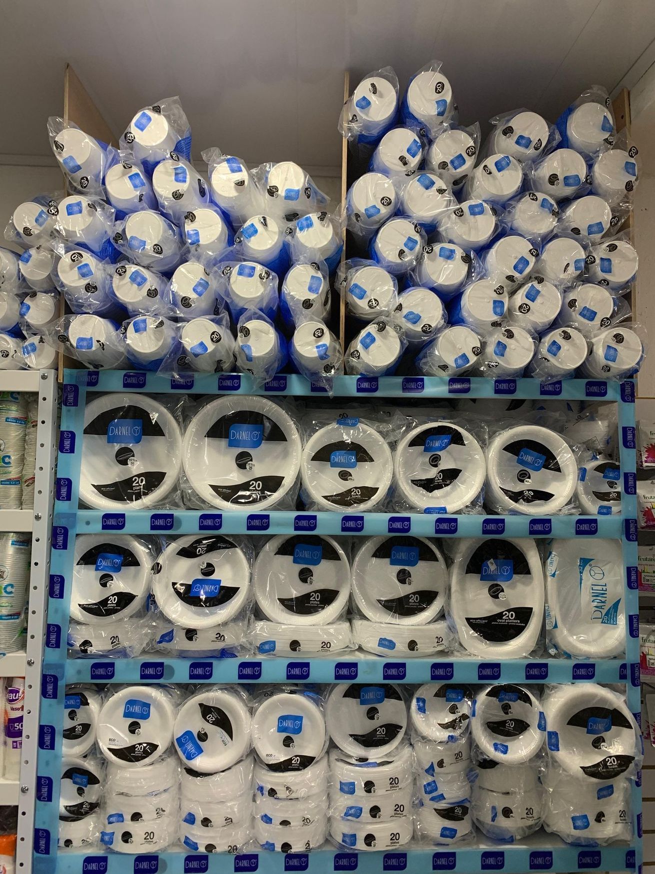 Estantería de tienda abastecida con rollos apilados de papel higiénico y toallas de papel blancos y azules