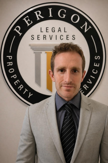 Man in light gray suit standing before Perrigon Legal Services logo wall