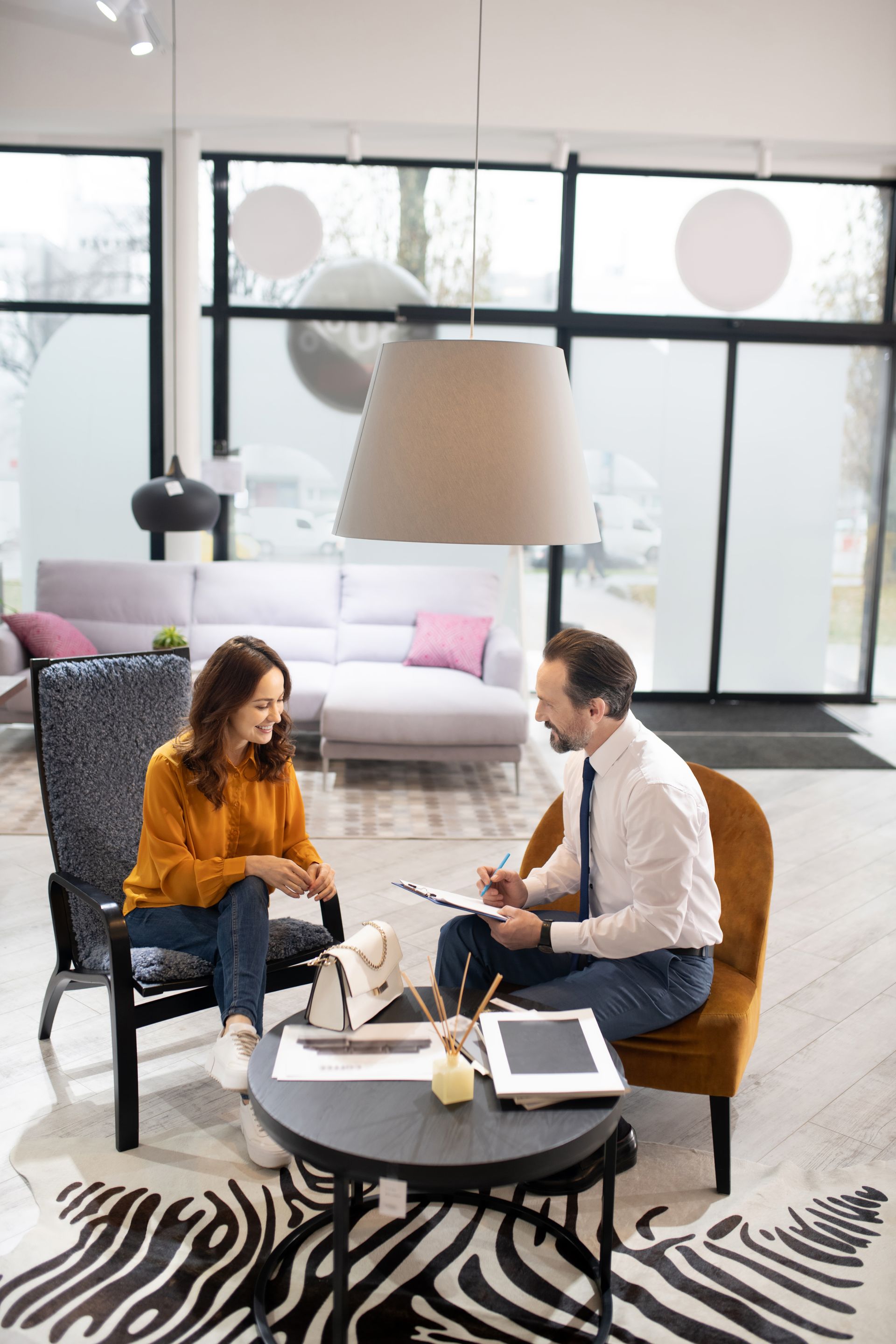 Two people in a modern living room discussing over coffee at a round table