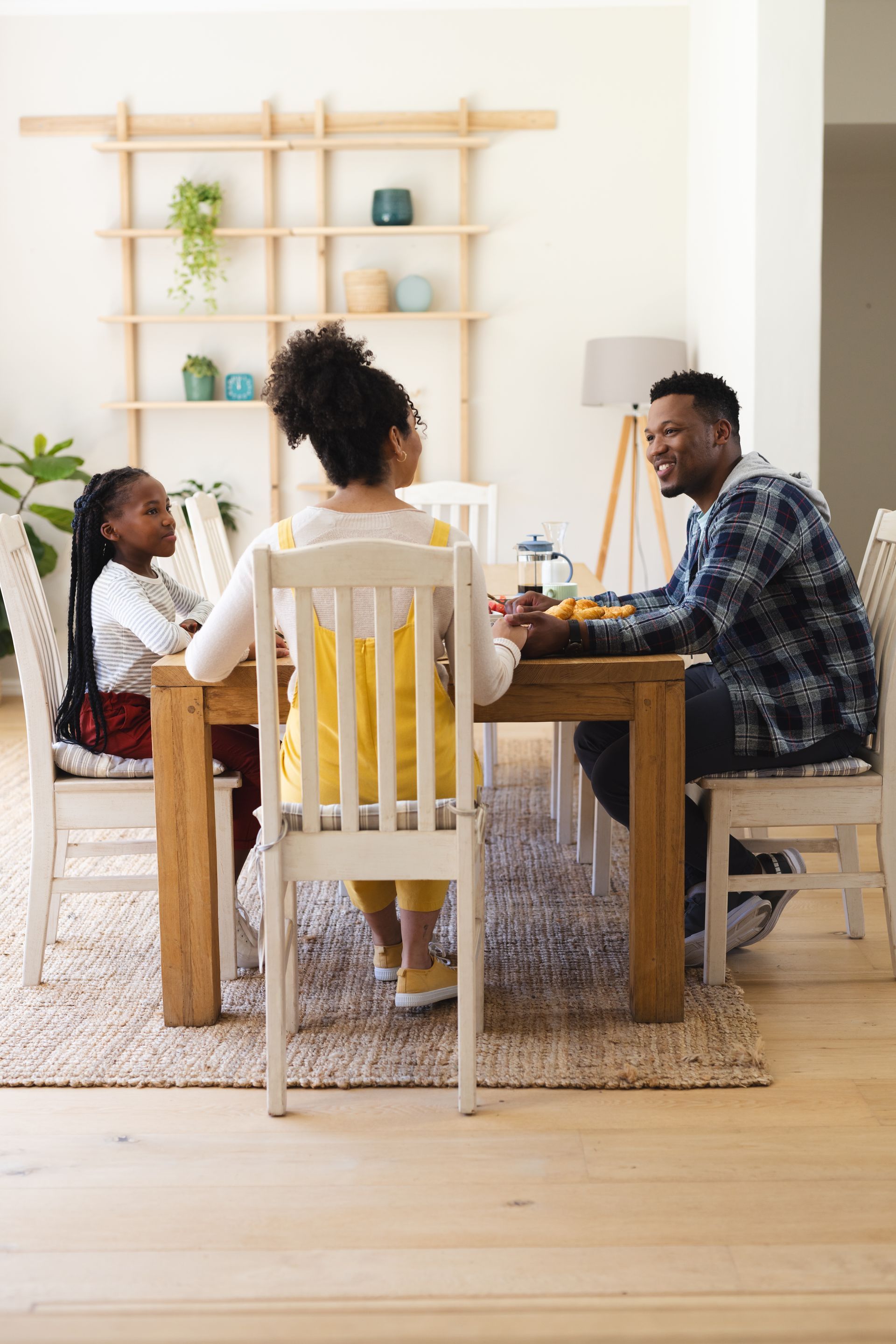 Family seated around a dining table in a bright living room, sharing a meal and conversation.