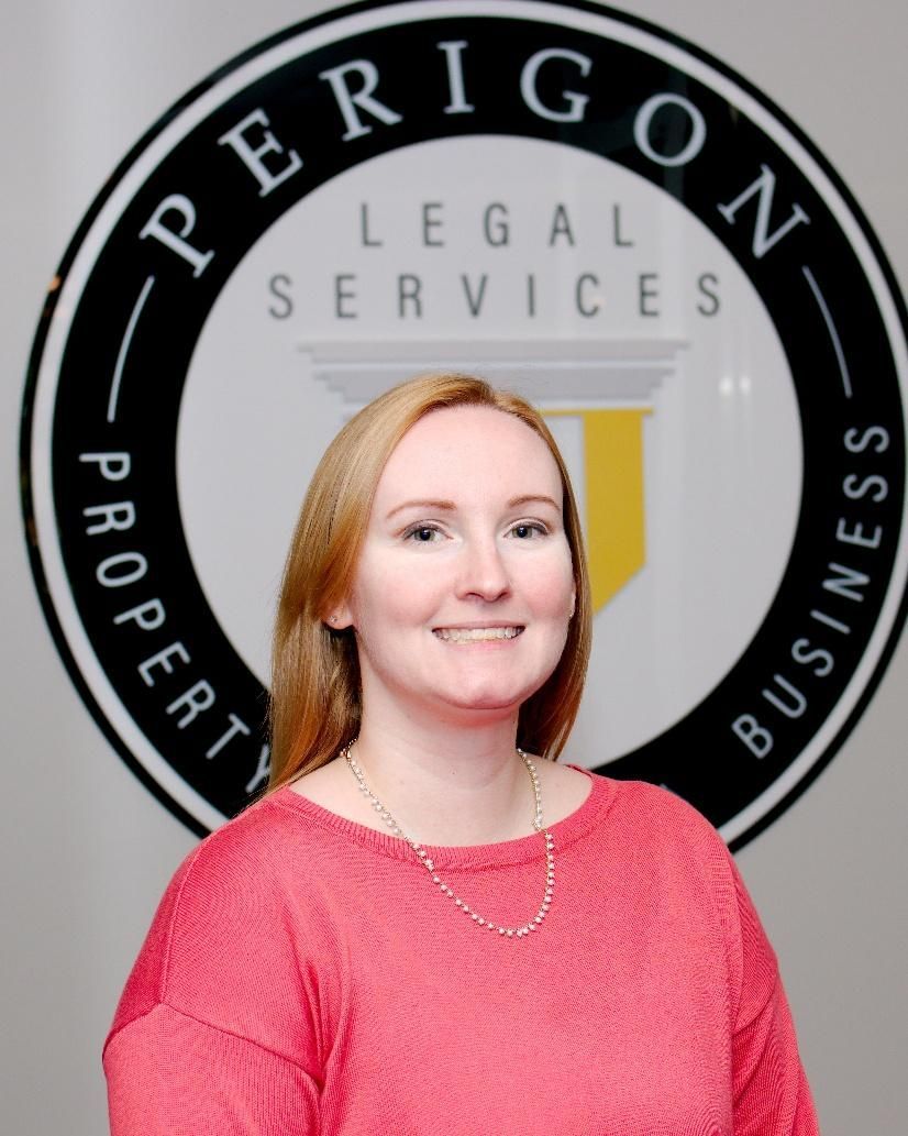 Woman in a pink top standing before a Perigon Legal Services logo backdrop.