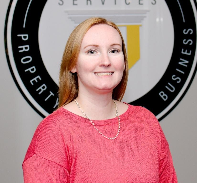 Woman in a pink top smiling in front of a business services sign
