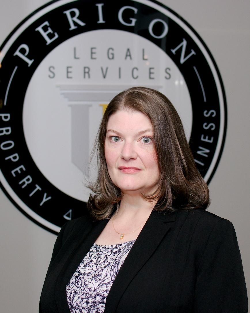 Woman in a black blazer standing before a Perrigon Legal Services logo backdrop.