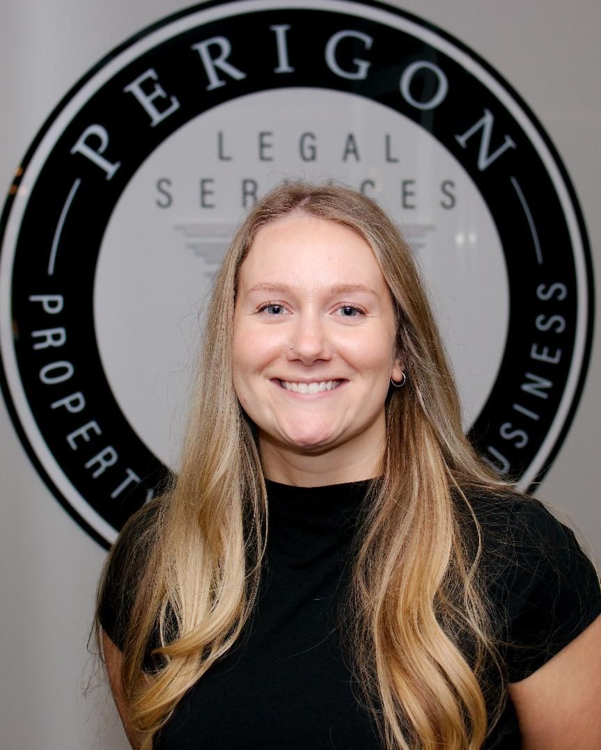Smiling person in black shirt before a Perigon Legal Services logo backdrop
