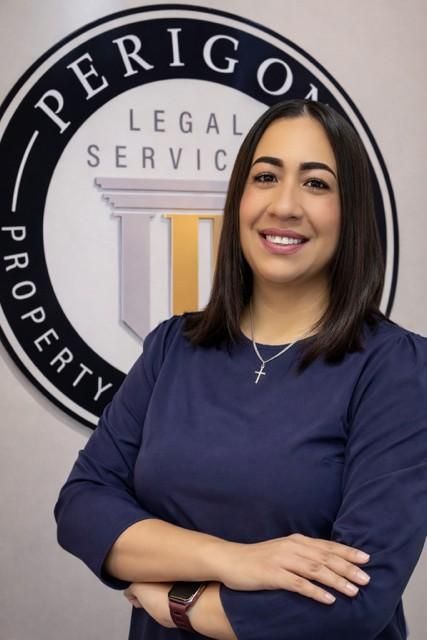 Portrait of a smiling woman in navy scrubs standing before a Perigon Legal Services sign