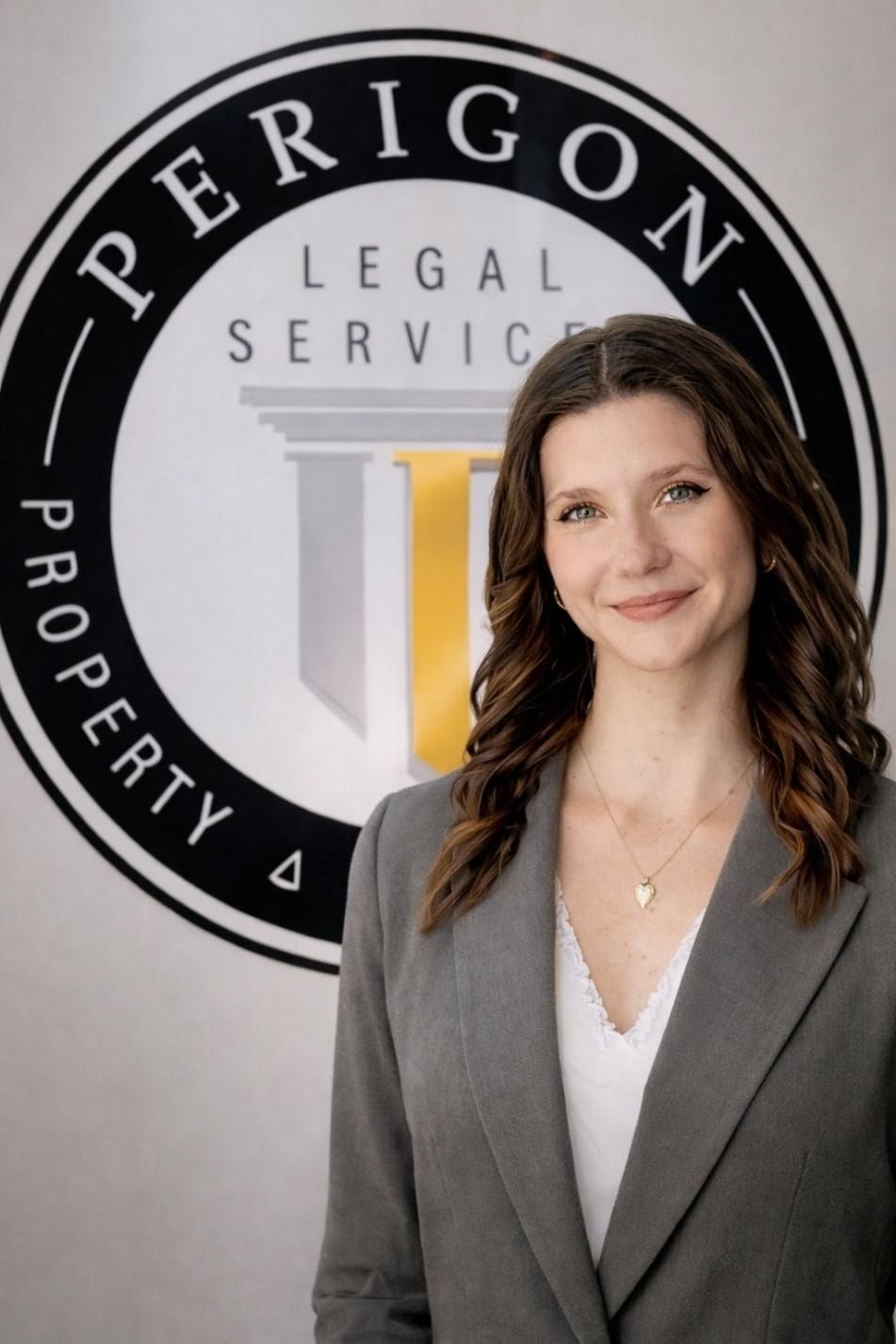 Portrait of a woman in a gray blazer before a Perigon Legal Services logo