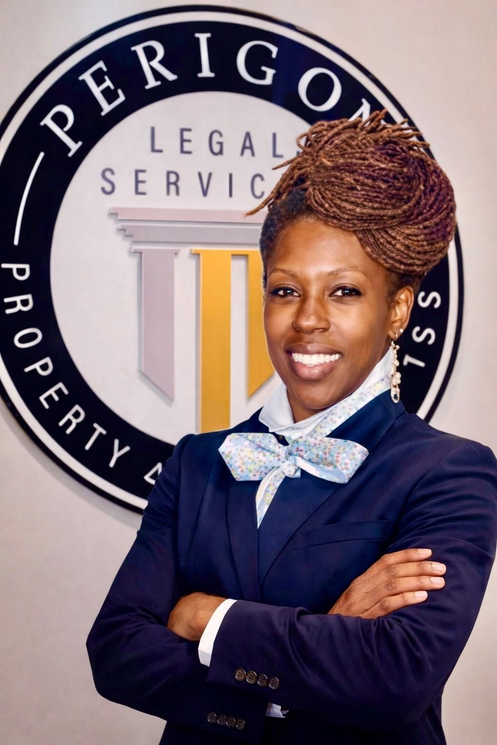 Professional woman in navy suit standing before a legal services sign, arms crossed and smiling