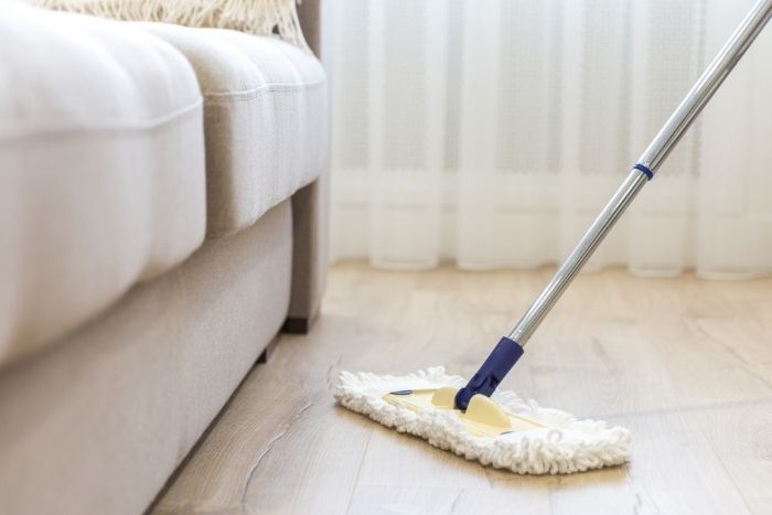 A Mop is Being Used to Clean a Wooden Floor in a Living Room — Lease Clean Newcastle in Newcastle, NSW