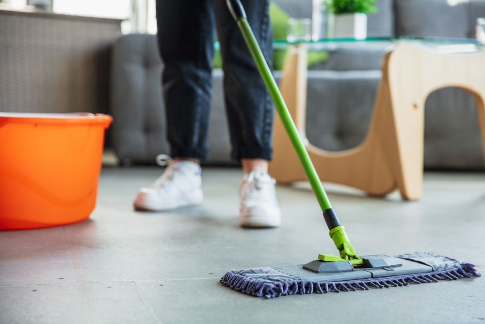 A Person is Mopping the Floor in a Living Room — Lease Clean Newcastle in Kotara, NSW