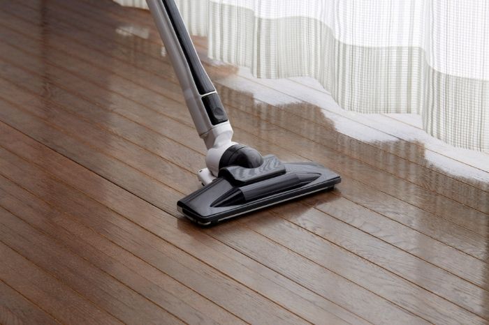 A Vacuum Cleaner is Being Used to Clean a Wooden Floor — Lease Clean Newcastle in Charlestown, NSW