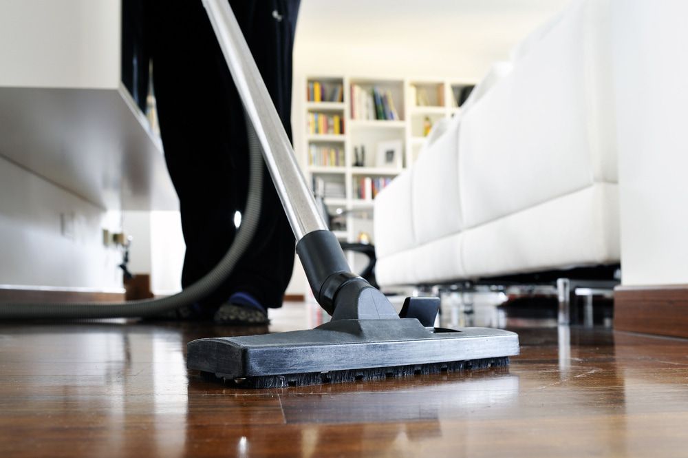 A Person is Using a Vacuum Cleaner to Clean the Floor in a Living Room — Lease Clean Newcastle in Newcastle, NSW