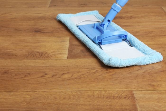 A Mop is Being Used to Clean a Wooden Floor — Lease Clean Newcastle in Charlestown, NSW