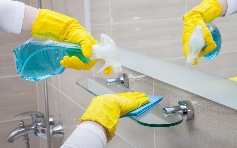 A Person is Cleaning a Bathroom Mirror — Lease Clean Newcastle in Newcastle, NSW