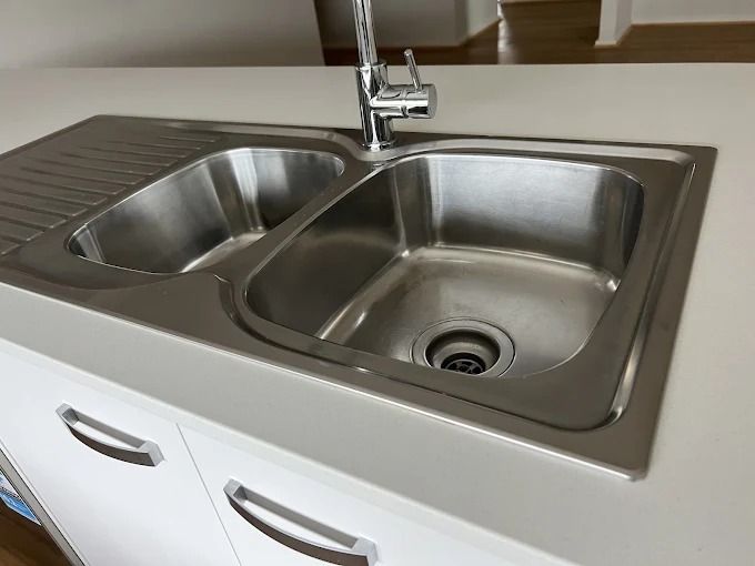 A Person is Cleaning a Stove Top With a Towel — Lease Clean Newcastle in Charlestown, NSW