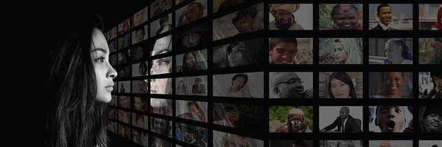 A Woman Is Looking at an Array of Humanity But Sees Only a Reflection of Herself