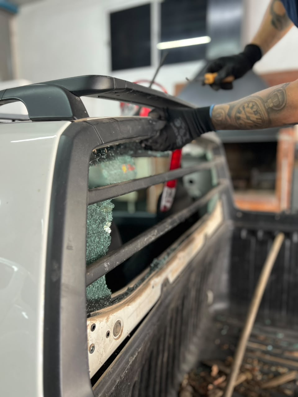 Técnico instalando un parabrisas de coche con embellecedor negro en un taller.