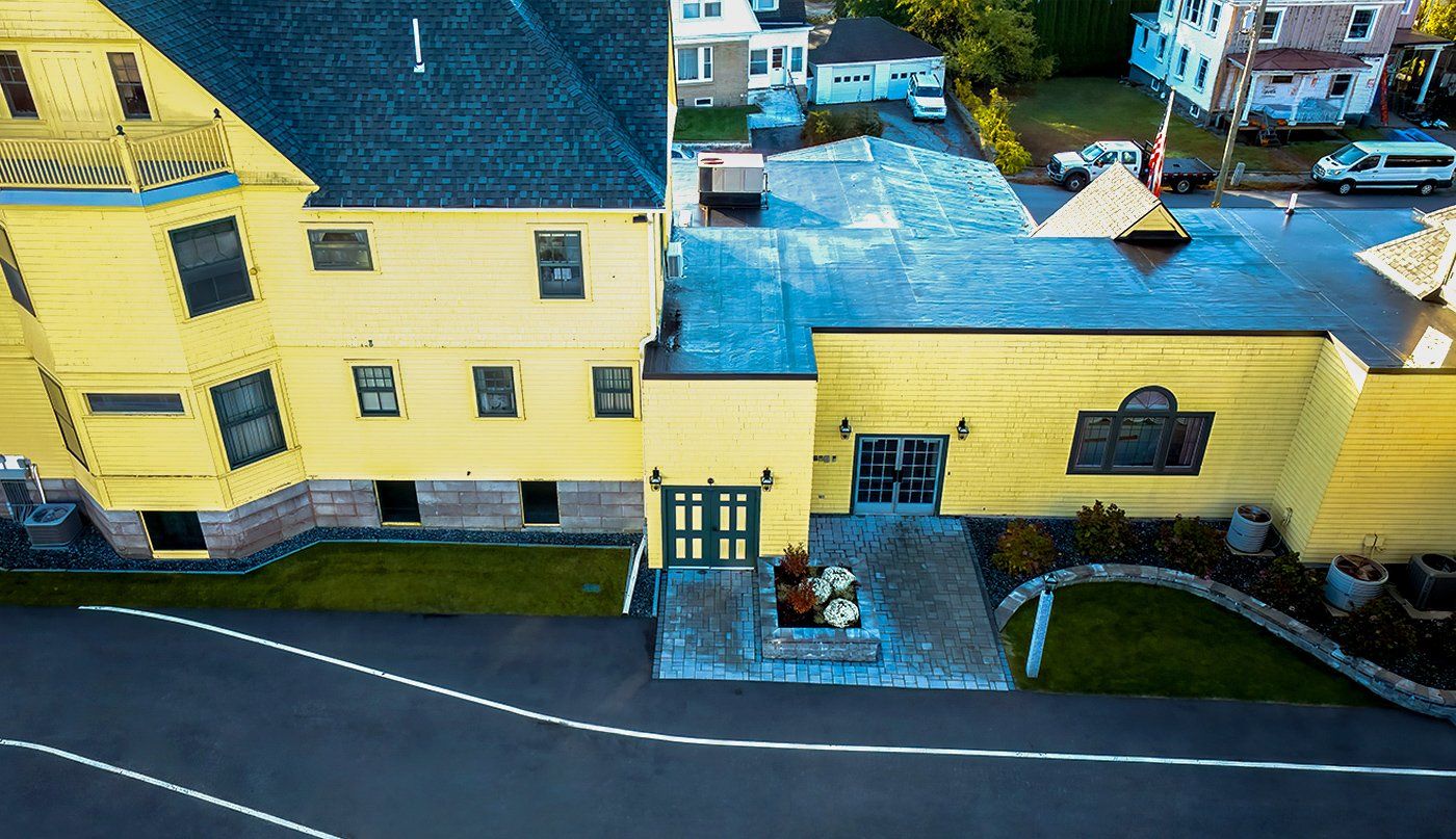 An aerial view of a yellow house with a blue roof