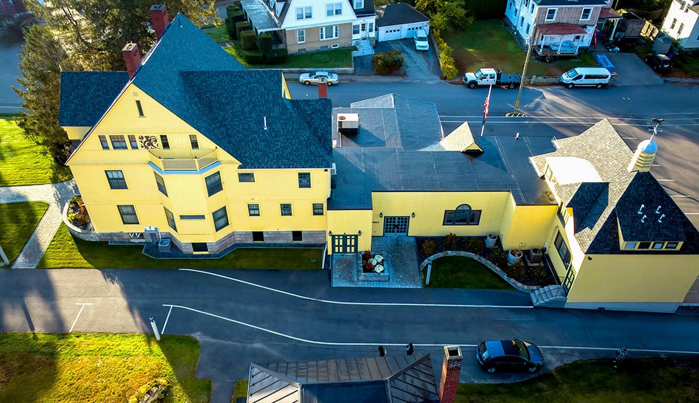 An aerial view of a yellow building with a black roof