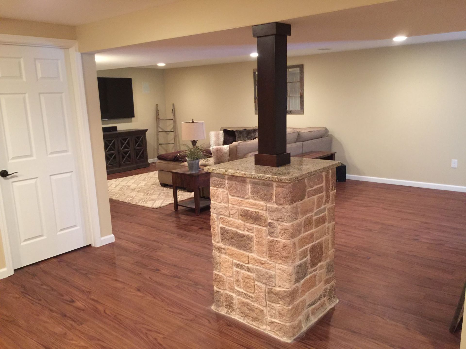 A living room with hardwood floors and a stone fireplace.