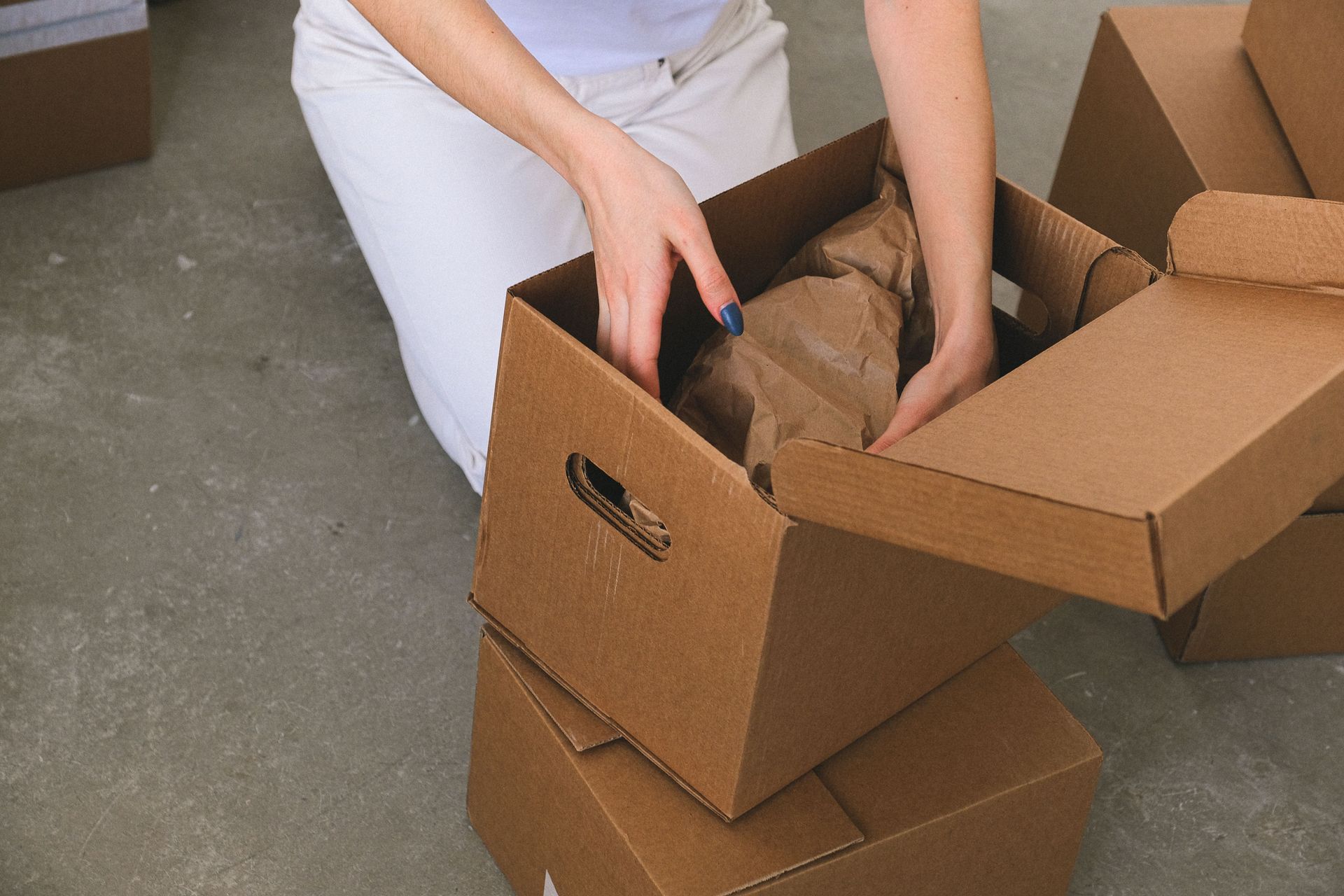Modern living room on moving day, with neatly stacked cardboard boxes of various sizes and labels.