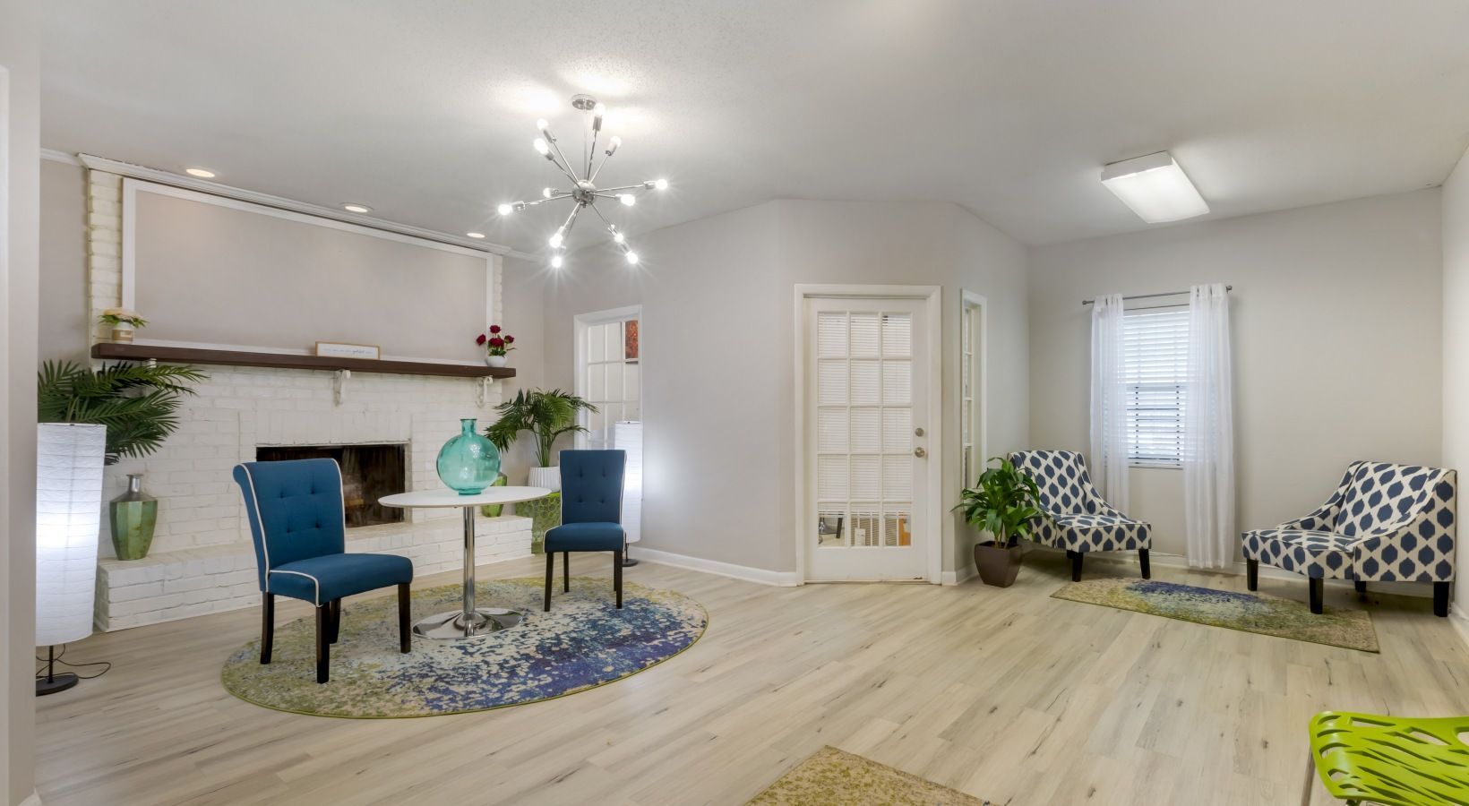 Bright room with fireplace, blue chairs, white table, and patterned armchairs.