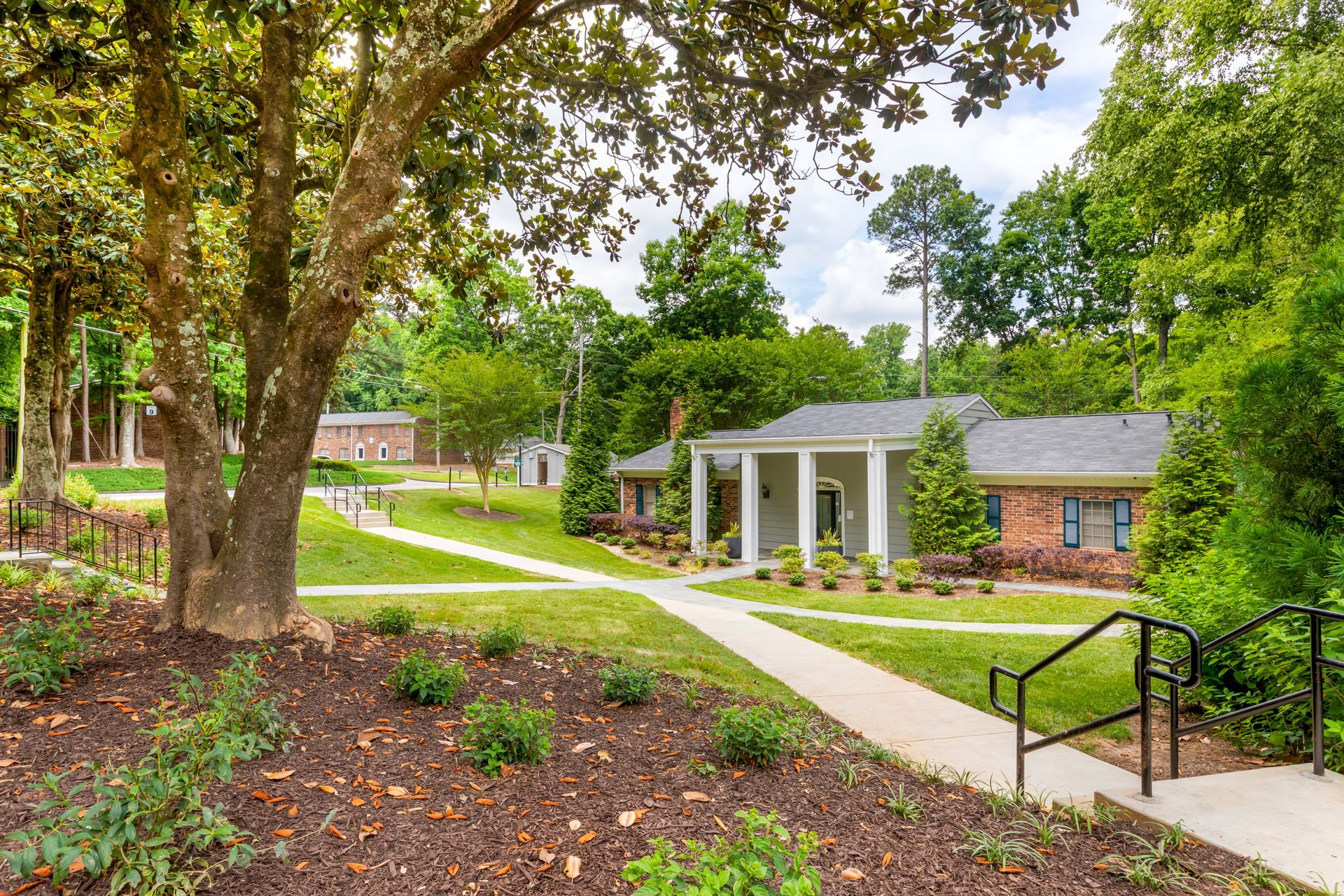 Row of two-story townhouses with turquoise doors, parked cars on the side, and grassy area.