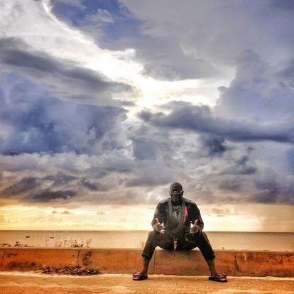 A man is sitting on a wall next to the ocean.