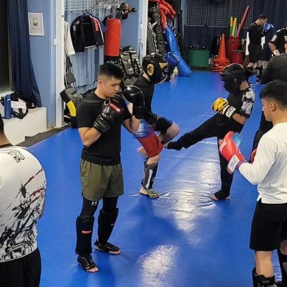 A group of men are boxing on a blue mat in a gym