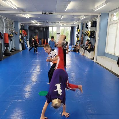 A group of kids are doing a handstand in a gym
