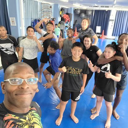 A group of people are posing for a picture including a man wearing a shirt that says gracie carry