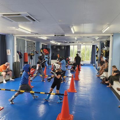A group of people are boxing in a gym surrounded by cones.