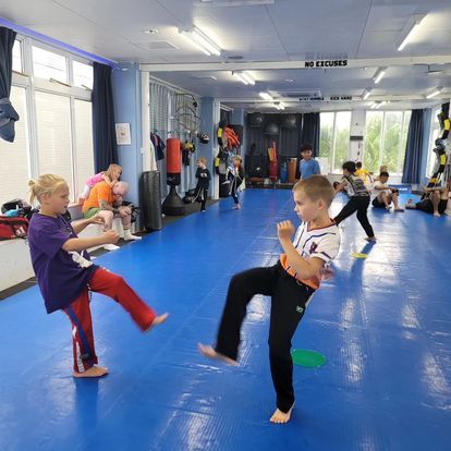 A group of children are practicing martial arts in a gym