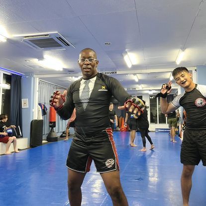 Two men are posing for a picture in a gym.